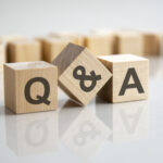 Q and A of what to ask a lawyer during a consultation - an abbreviation of wooden blocks with letters on a gray background. Reflection of the Q and A caption on the mirrored surface of the table. Selective focus.
