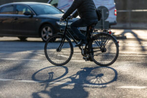 cyclist with black bike in backlight near distracted driving causing accidents between motor vehicles and bicyclists 