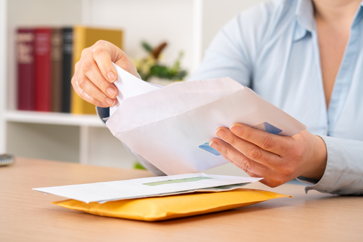 Close up of woman hands putting a letter inside an envelope with a bill